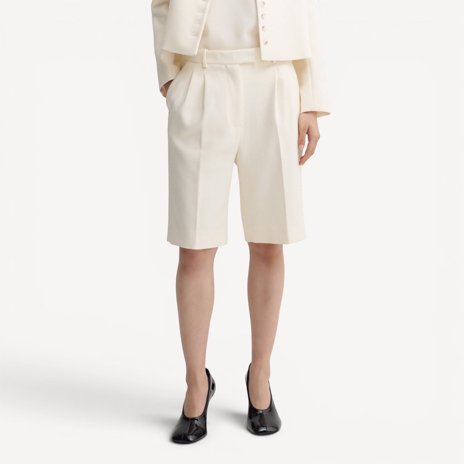Lula Studio Prague cream woven blend shorts with front pleats and adjustable side tabs, falling above the knee.